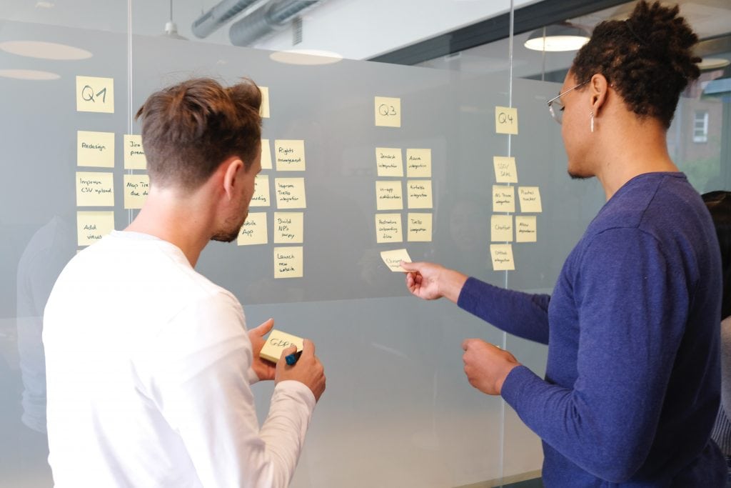 two workers using sticky notes on a wall