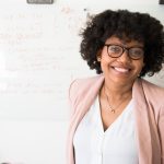 woman with brown curly hair and glasses smiling at the camera