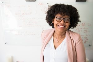 woman with brown curly hair and glasses smiling at the camera