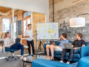 Group of men planning a project on a whiteboard. Blog cover image for MindGenius website.